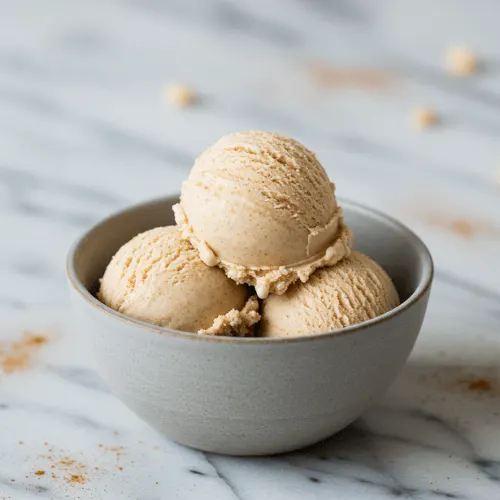 A scoop of So Delicious Snickerdoodle ice cream with cinnamon specks in a bowl, highlighting its cashew milk base.