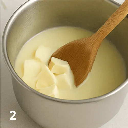 Melting white chocolate in a bowl with warm milk and butter for pistachio cream.