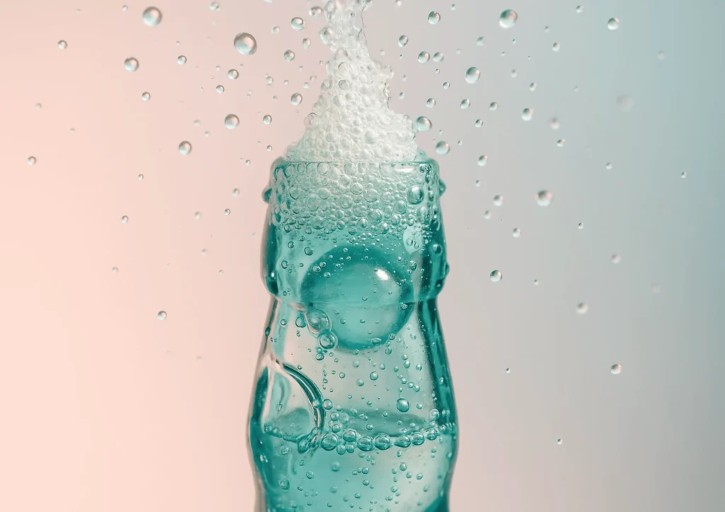 A close-up of a Ramune soda bottle as the marble is pushed in, with fizz and bubbles captured mid-action.