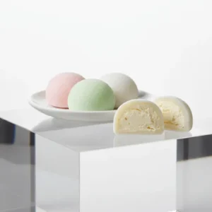 Colorful mochi ice cream pieces with chewy rice dough and creamy ice cream filling on a white table.