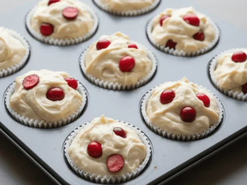 Filled muffin liners with cranberry-studded batter ready to go into the oven.