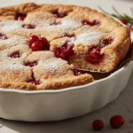 A golden-brown Nantucket Cranberry Pie with cranberries peeking through the surface, showcasing its signature crustless cake texture.