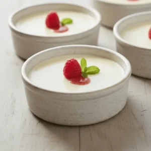 Classic Italian panna cotta served with fresh berries and fruit sauce, showcasing its smooth and creamy texture.