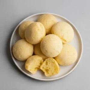 Freshly baked Brazilian cheese bread with a golden crust and soft, stretchy interior served on a ceramic plate.