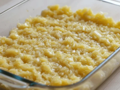 Crushed pineapple evenly spread in a baking dish before adding cake mix. This step forms the juicy base of pineapple dump cake.