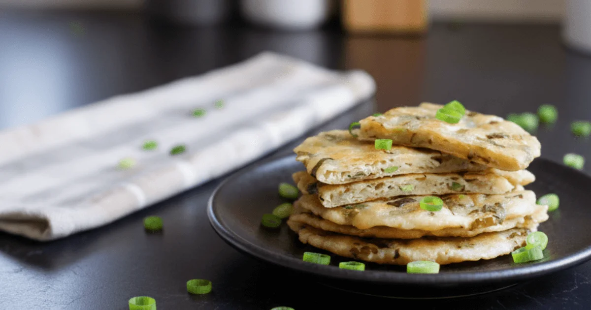 Crispy Chinese scallion pancakes stacked on a plate, showing flaky layers and a golden crust. Perfect example of homemade pan-fried scallion pancakes.