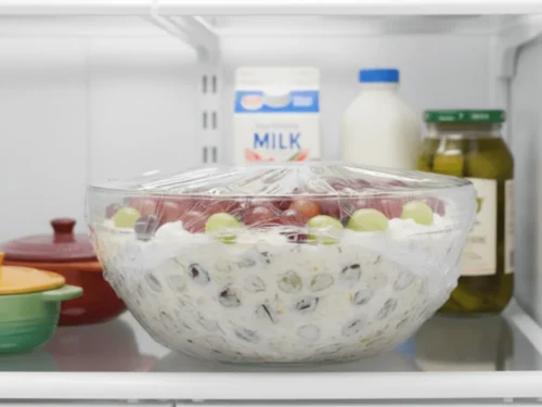 Bowl of grape salad covered and placed in the fridge for chilling before serving
