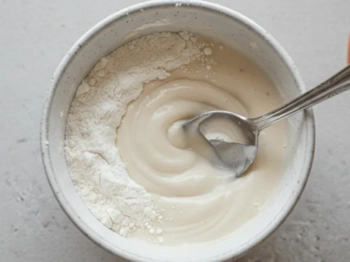 Protein mug cake batter being mixed in a mug using protein powder, flour, and milk.