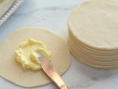 A stack of rolled Danish pastry dough circles with butter between each layer, ready for freezing.