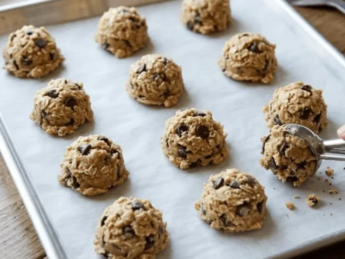Scoops of oatmeal cookie dough placed on a baking tray ready for baking. Spacing the cookies allows them to spread evenly.